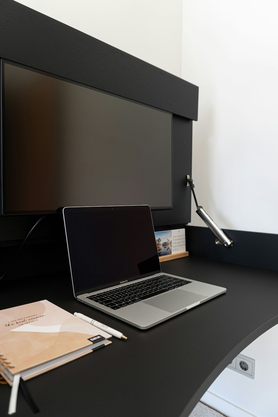 Laptop und Notizbuch auf einem modernen Schreibtisch im Homeoffice.
