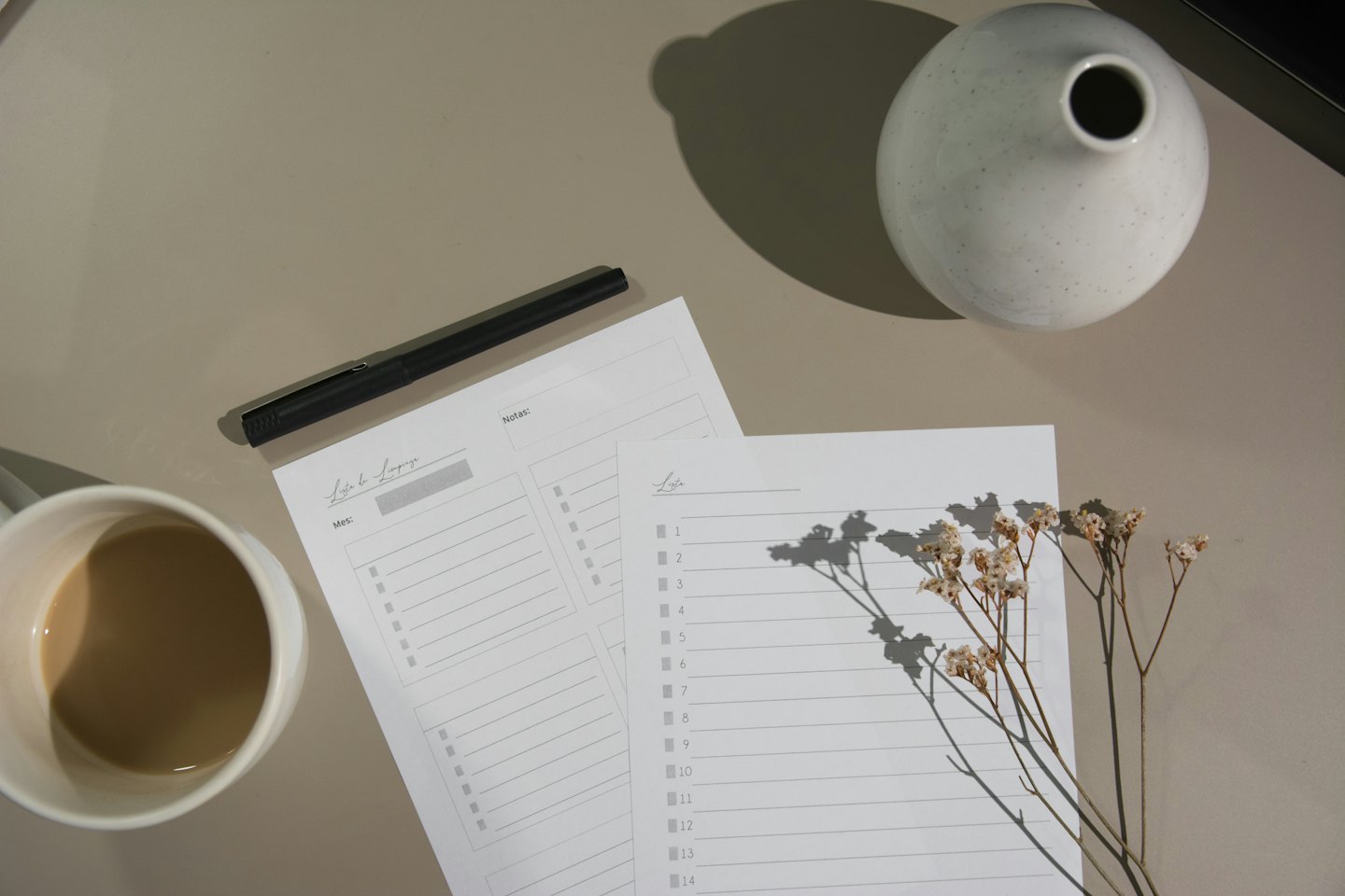 Schreibtisch-Aufnahme von oben mit Kaffee, Planer und Blumen.