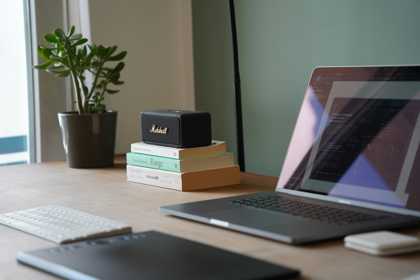 Laptop, Bücher und Lautsprecher auf einem Holztisch.