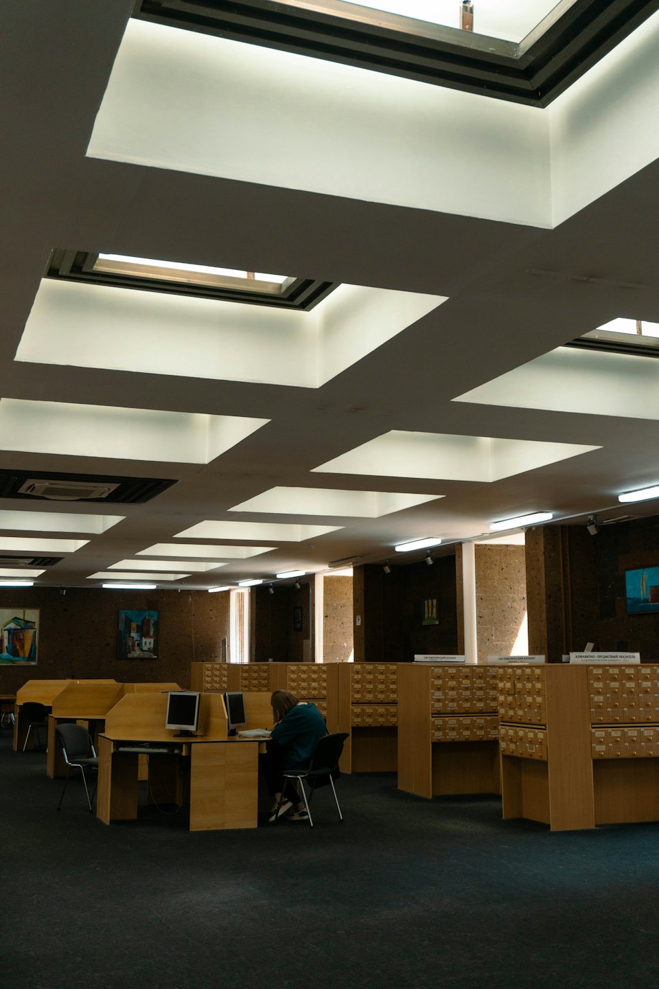 Eine Person arbeitet an einem Schreibtisch in einer modernen Bibliothek.